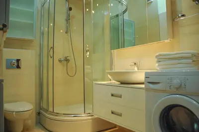 a bathroom with a shower and a sink and a washing machine at Andreja Apartment in Budva