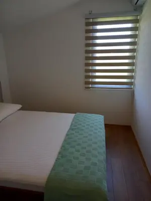 a small bedroom with a bed with a window at Apartman Borka Rezevici in Krstac