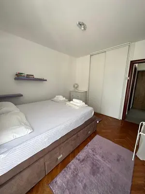 a bedroom with a large white bed with a purple rug at Apartment Mediteraneo in Budva