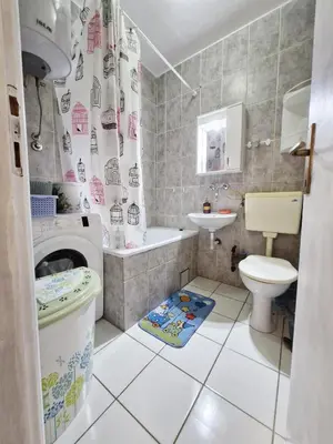 a bathroom with a toilet sink and a washing machine at Ilino Studio Apartment in Bar