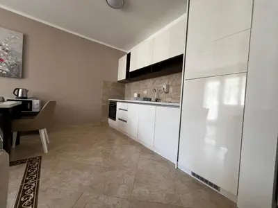a kitchen with white cabinets and a table at Apartment Zevs Bečići in Kravlja