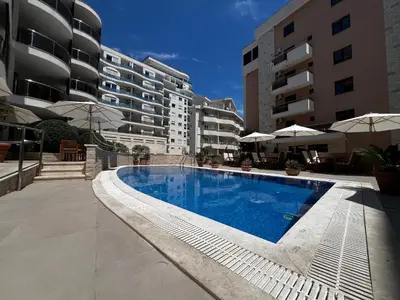 a swimming pool in front of some apartment buildings at Apartment Zevs Bečići in Kravlja
