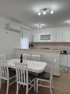 a kitchen and dining room with a white table and chairs at Lukic Guest house in Ulcinj