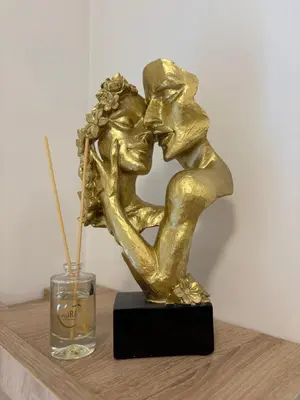 a gold kissing couple statue next to a glass at Apartments Masa in Podgorica