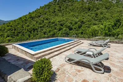 a swimming pool with two lounge chairs and a swimming poolvisor at Wild silence - Skadar Lake in Virpazar