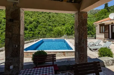 a swimming pool in a patio with two chairs and a table at Wild silence - Skadar Lake in Virpazar