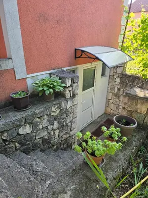 a building with a stone wall with a door and potted plants at Apartman Knez 1 in Podgorica