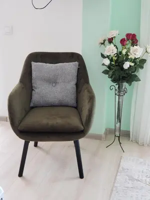 a brown chair with a pillow next to a vase of flowers at Уютная квартира в частном секторе , идеальный отдых у моря in Bar