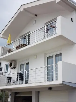 a white apartment building with a balcony and an umbrella at Уютная квартира в частном секторе , идеальный отдых у моря in Bar