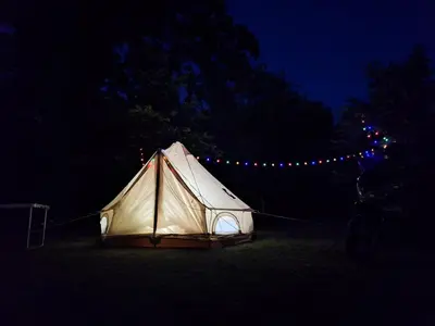 a tent is lit up in a field at night at Whispering Waters