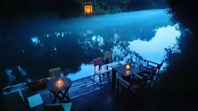 a table and chairs next to a lake at night at Whispering Waters