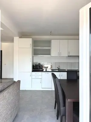 a kitchen with white cabinets and a table and a couch at Lotus in Donji Štoj