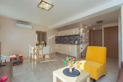 a living room with a yellow chair and a table at Galija lux Petrovac in Petrovac na Moru