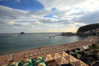 a beach with umbrellas and people on the beach at Galija lux Petrovac in Petrovac na Moru