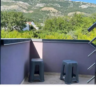 a balcony with two stools and a view of mountains at Apartmani Lucija Sutomore in Sutomore