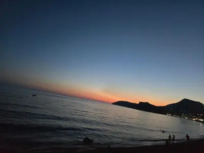 a group of people standing on the beach at sunset at Apartmani Lucija Sutomore in Sutomore