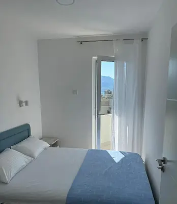a white bedroom with a bed and a window at The View Apartment in Budva
