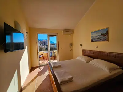 a bedroom with a bed with a television and a balcony at Apartments Premier in Budva