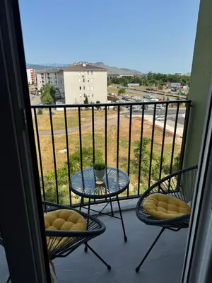 a balcony with a table and chairs and a view of a field at Apartment 43 with Garage in Podgorica