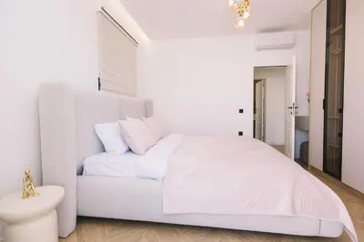 a white bedroom with a white bed and a sink at Azanti Residence in Ulcinj