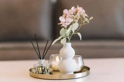 a white vase with flowers in it on a gold tray at Azanti Residence in Ulcinj