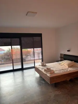 a bedroom with a bed in a room with large windows at Vila Enesa in Dobra Voda