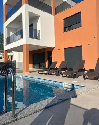 a building with a swimming pool and chairs next to a building at Vila Enesa in Dobra Voda