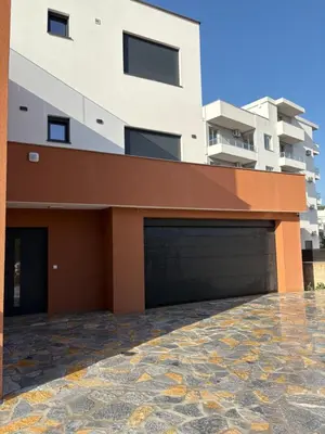 a building with two garage doors in front of it at Vila Enesa in Dobra Voda