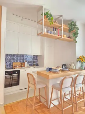 a kitchen with white cabinets and a wooden table and chairs at Sea Colours Apartment Budva in Budva