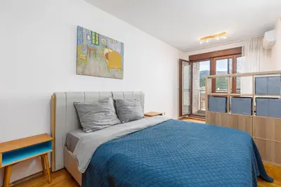 a bedroom with a blue bed and a window at Just 7 Min from the Beach Stylish 2BR in Becici