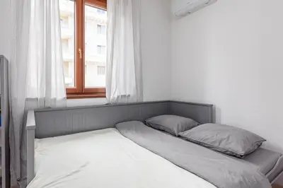 a bed with two pillows in a room with a window at Just 7 Min from the Beach Stylish 2BR in Becici
