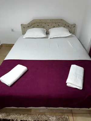 a bed with two white pillows and a purple blanket at Sara s Apartments in Ulcinj