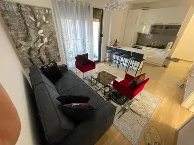 a living room with a black couch and red chairs at Lux apartment Ruzmarin in Becici