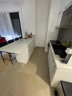 a white kitchen with a sink and a table at Lux apartment Ruzmarin in Becici