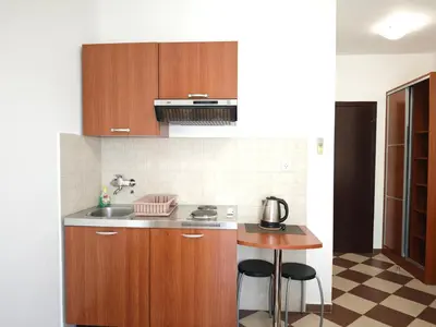 a kitchen with wooden cabinets and a sink and a table at Guest House Anika in Becici