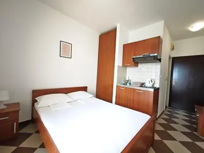 a bedroom with a large bed and a kitchen at Guest House Anika in Becici