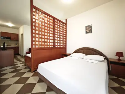 a bedroom with a white bed and a checkered floor at Guest House Anika in Becici