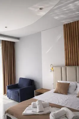 a bedroom with a bed and a blue chair at Hotel Adler in Ulcinj