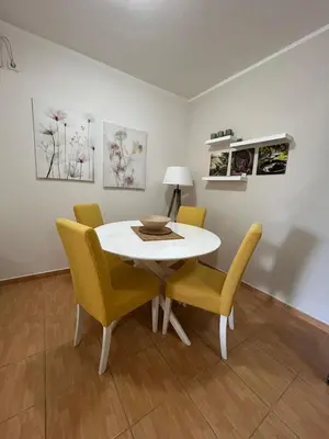 a dining room with a white table and yellow chairs at Apartment Elena in Prijevor