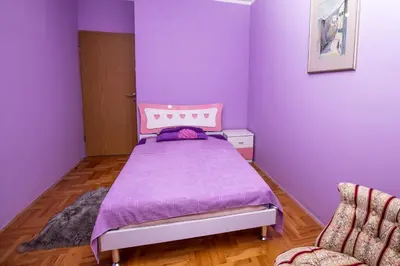 a purple bedroom with a bed and a chair at Apartment Sole in Cetinje