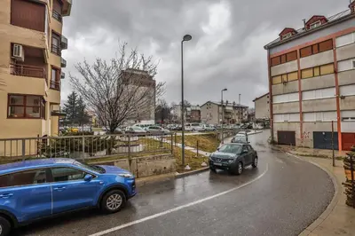 two cars driving down a city street in the rain at Apartment Sole in Cetinje