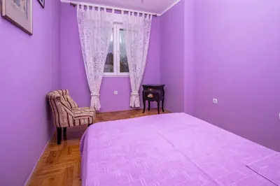 a purple bedroom with a bed and a window at Apartment Sole in Cetinje