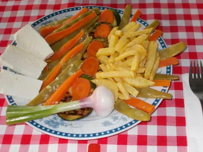 a plate of vegetables and french fries on a table at Guesthouse Feel Lake in Virpazar