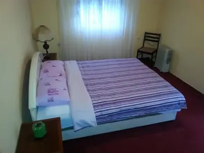 a bedroom with a large bed with purple sheets and a chair at Guesthouse Feel Lake in Virpazar