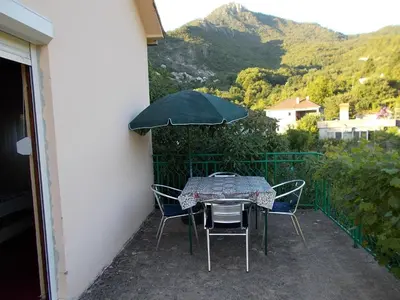 a table and chairs with an umbrella on a balcony at Guesthouse Feel Lake in Virpazar