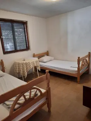 a room with two beds and a table and a window at Apartman Nina in Donji Štoj
