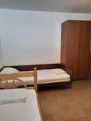 a bedroom with two beds and a wooden cabinet at Apartman Nina in Donji Štoj