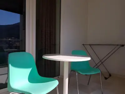 a white table and two green chairs in a room at Apartment TC Lux VLSB in Budva