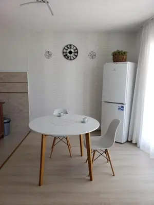 a white table and chairs in a kitchen with a refrigerator at Уютная 1-комнатная квартира с видом на море! in Bar