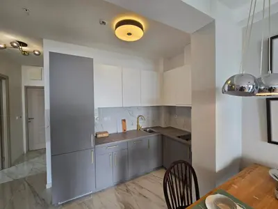 a kitchen with white cabinets and a table and a dining room at Green Stone lamela B in Rafailovici